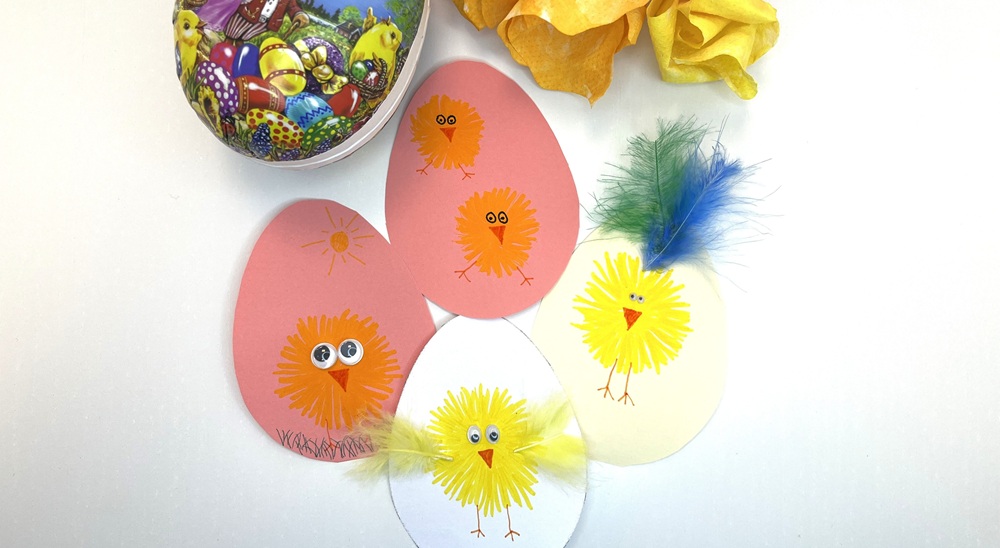 Färgglad påskdekoration med ett stort illustrerat påskägg, målade pappersägg med kycklingmotiv och färgglada silkespappersblommor